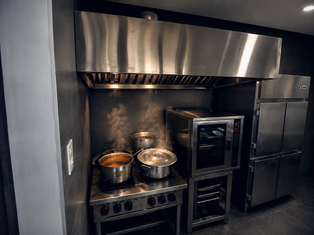 Coifa sobre fogão industrial e forno combinado em operação